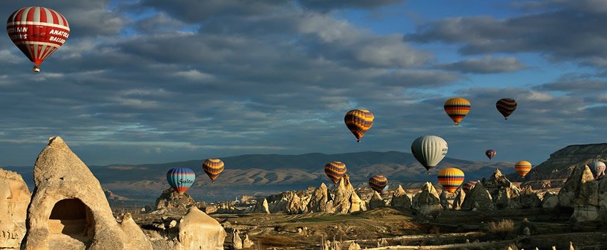 Hot-air balloons floating above Cappadocia rock formations