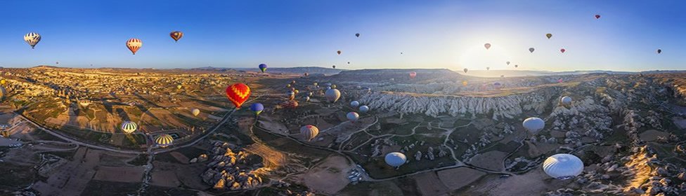 Dozens of balloons above Cappadocia at sunrise