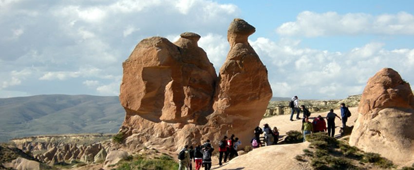Visitors walking among Cappadocia's red-rock fairy chimneys